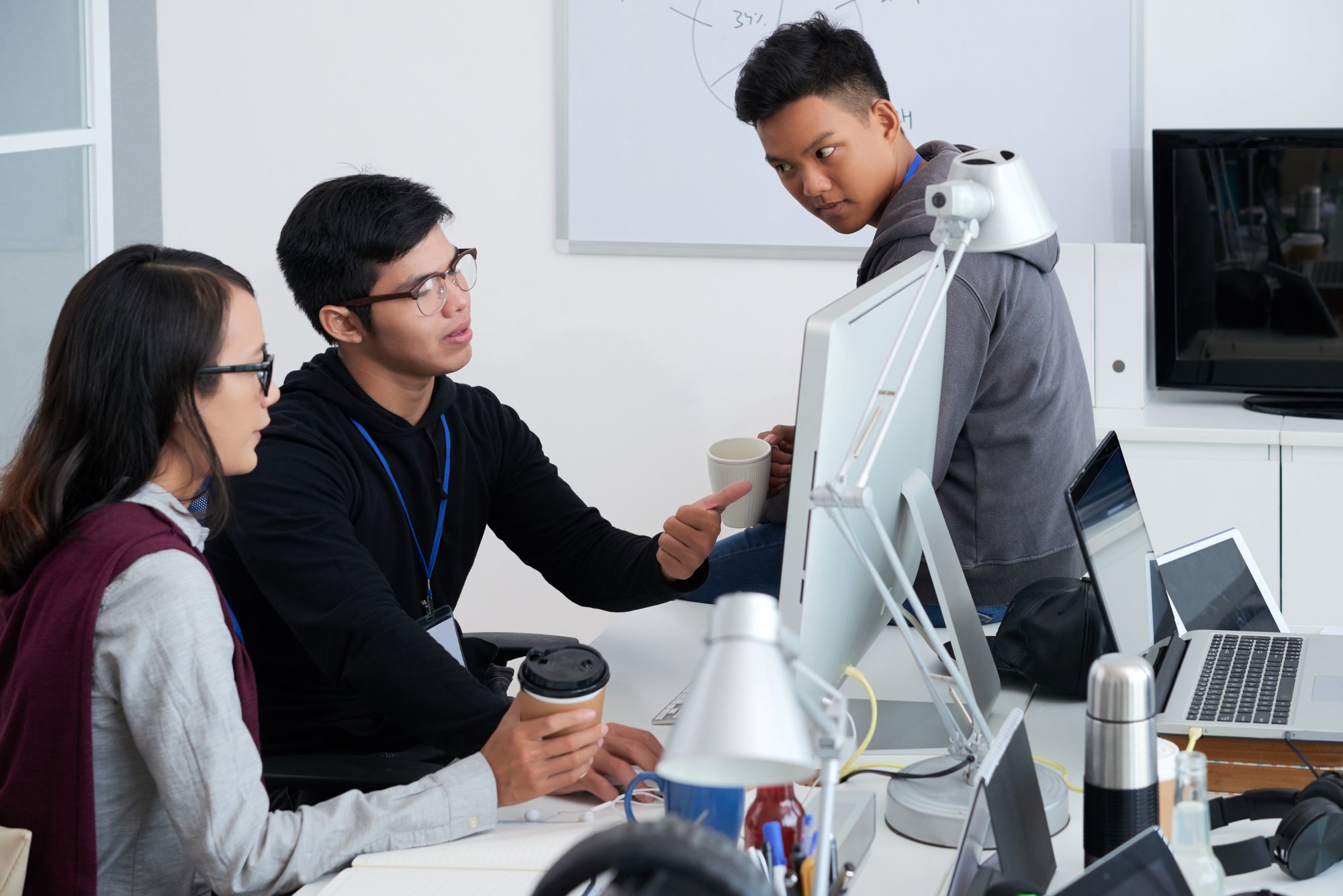 Developers collaborating around a computer monitor in an office